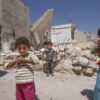 Syriske børn foran bombede huse